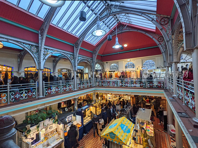 在卡姆登锁市场(Camden Lock Market)的中庭里，顾客们在工艺品摊位间穿行，顾客们在楼上浏览商店，阳光透过玻璃天花板照进来